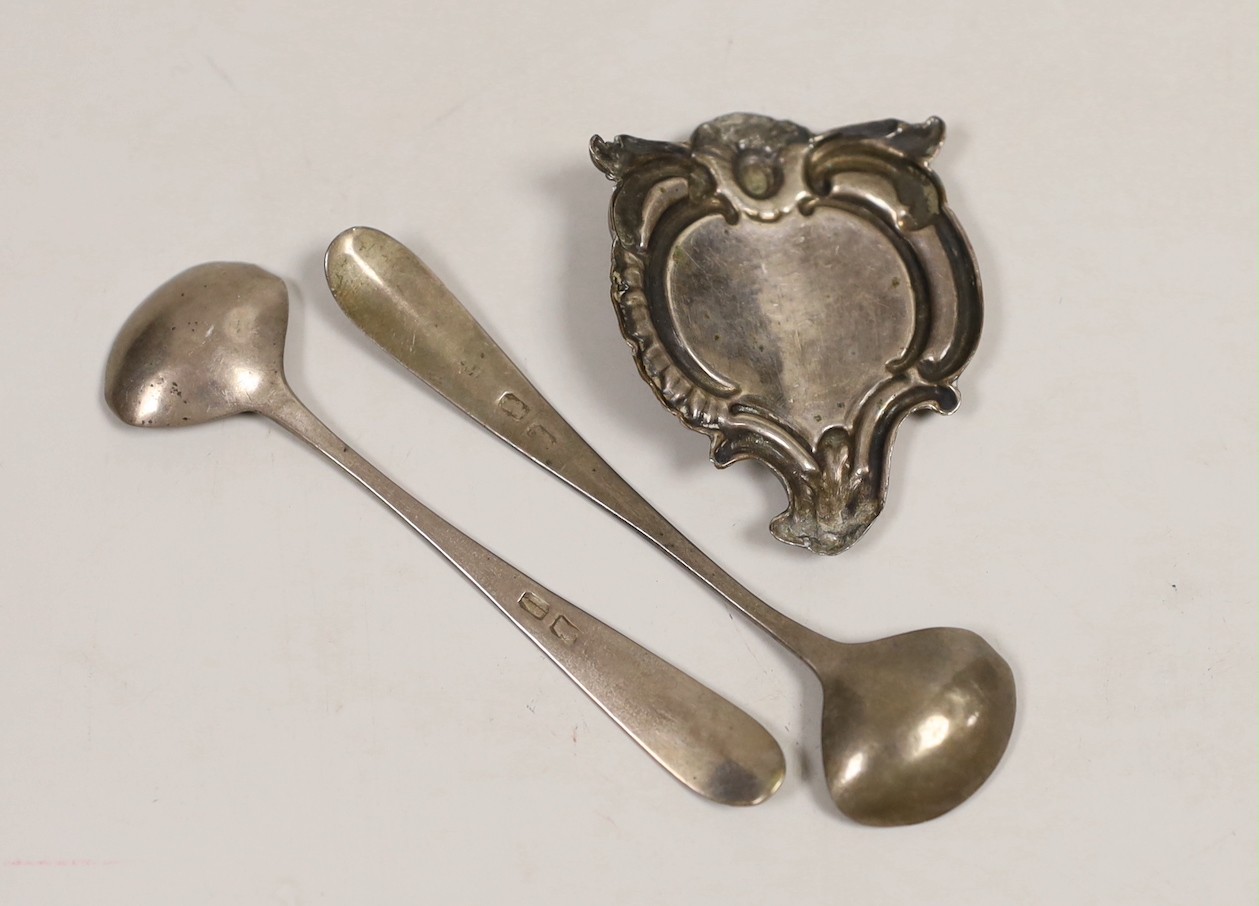 A George III silver glass coaster, William Plummer, London, 1781, 91mm, together with a pair of early 19th century Irish silver condiment spoons and a white metal cartouche.